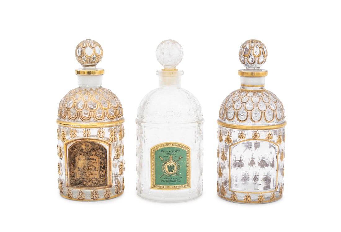 Guerlain Gilt Embossed Bee Cologne Bottles, 3: Group of Three Guerlain Gilt Embossed Bee Cologne Bottles, each with ball from stoppers, 19th century, comprising: two with gilt trim and accents, one with partially obliterated tan and black label an