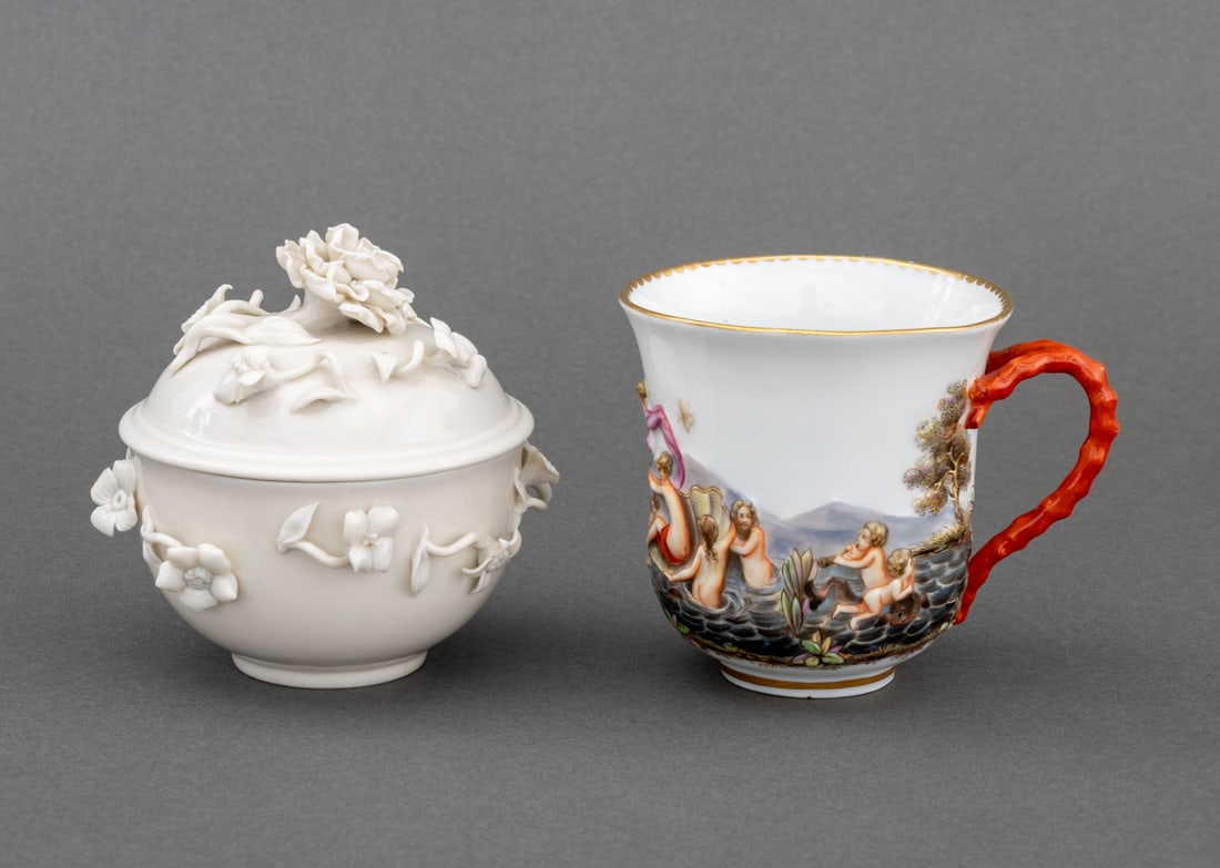 German Porcelain Tableware, 2 Pcs.: Group of Two German Porcelain Tableware Pieces, comprising: Meissen teacup with figural landscape relief scene, with blue double crossed sword mark to underside, and Nymphenburg covered cup, with