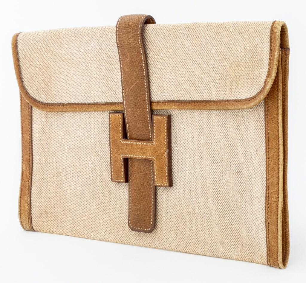 Hermes Leather and Toile "Jige" Clutch: Hermes Brown Leather and Beige Toile "Jige" Clutch, with leather trim, fold-over top with "H" slide closure, marked "Hermes Paris Made in France". 7.25" H x 11" W x 1" D. Property from the Estate of d