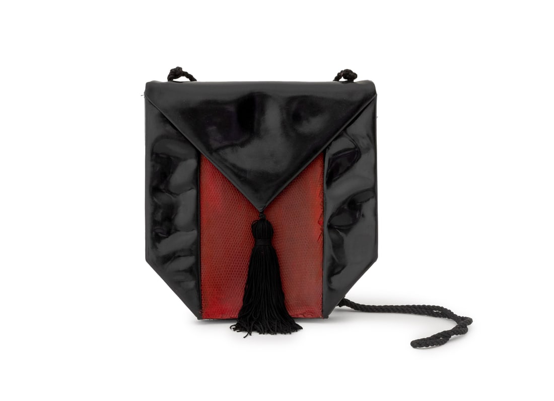 Yves Saint Laurent Black Patent Leather Handbag: Yves Saint Laurent Black Patent Leather Handbag, with red snakeskin embossed panel and tassel front flap, marked inside. 8" H x 8 W x 2" D. Provenance: From the Estate of American Fashion Journalist a