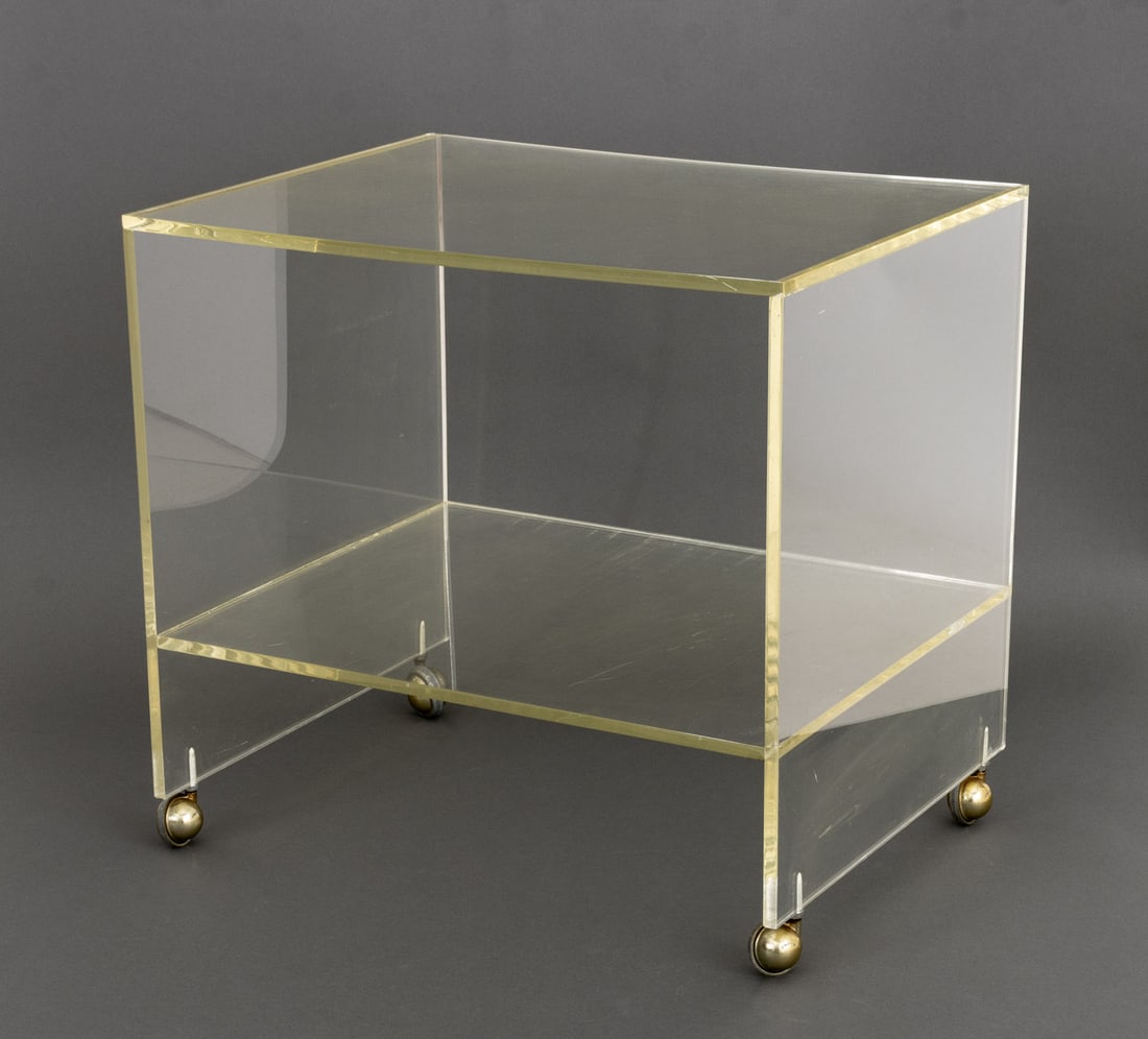 Charles Hollis Jones Style Lucite Rolling Table: Charles Hollis Jones Style Lucite Two-Tier Rolling Table, mounted on brass casters. 24.25" H x 26" W x 20" D. Provenance: From the Estate of American Fashion Journalist and Editor-in-Chief of Vogue (1