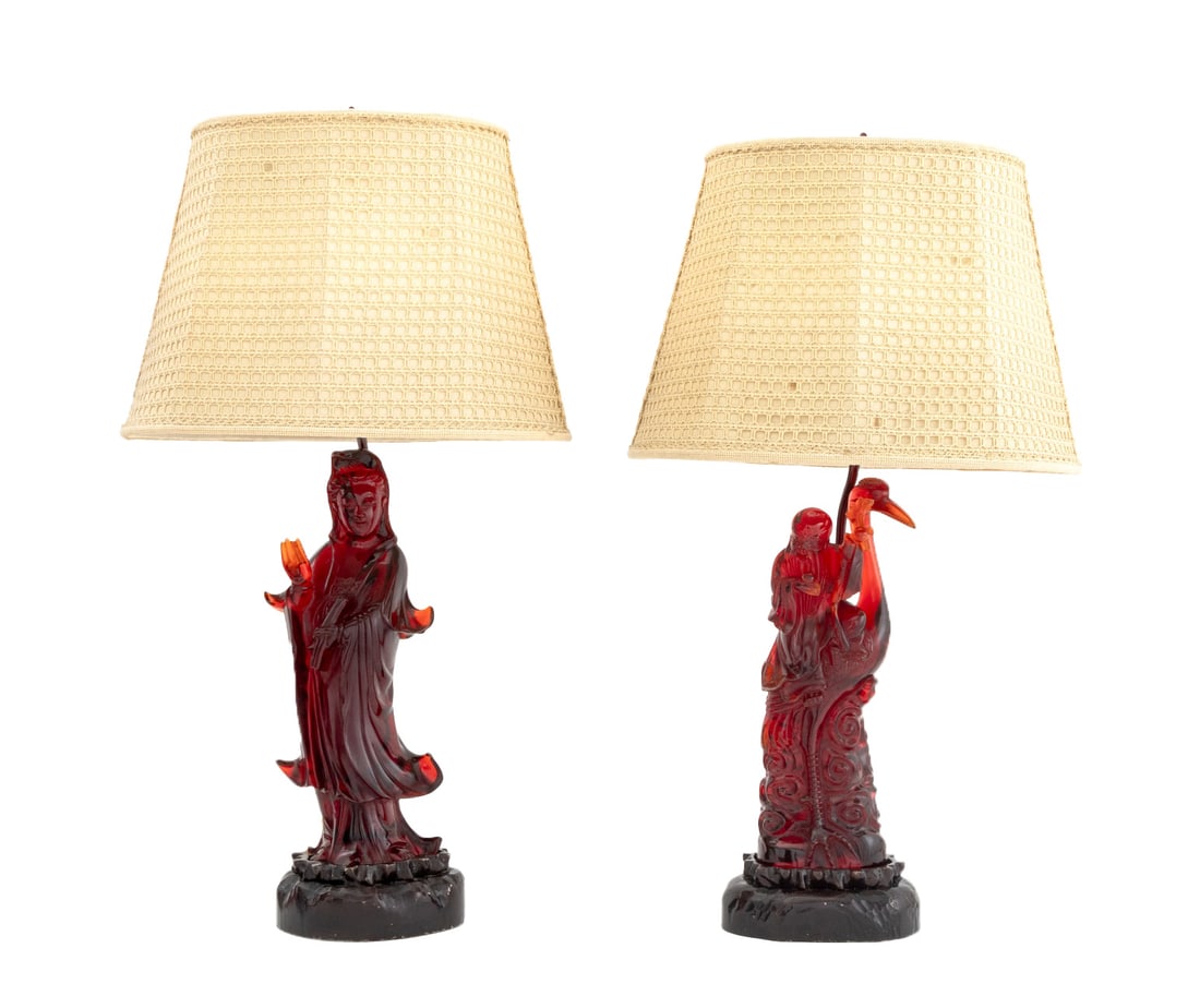 Chinese Cherry Red Amber Figural Table Lamps, Pair: Pair of Chinese Cherry Red Amber Figural Carvings Mounted as a Table Lamps, one Guanyin and one Shouxing atop a crane, each on wood base with crochet shades. Larger overall: 30.5" H x 15.5" W x 12"