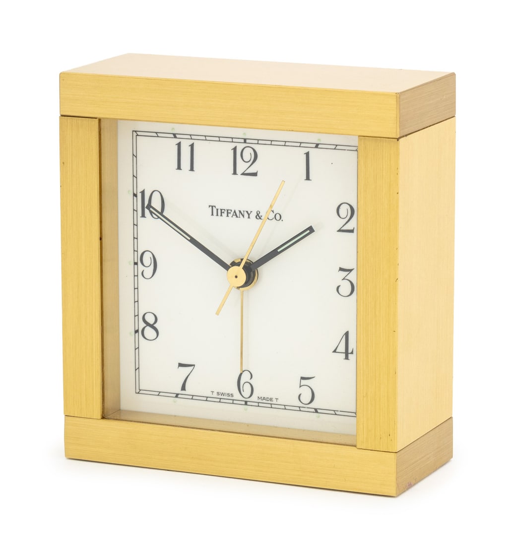 Tiffany & Co. Brass Desk Clock: Tiffany and Company Brass Desk Clock, white enamel clock face with black Arabic numbers, marked "Tiffany & Co. / Swiss Made" to dial. 3.5" H x 3.25" W x 1.5" D. Provenance: Property from a Bunny Willi