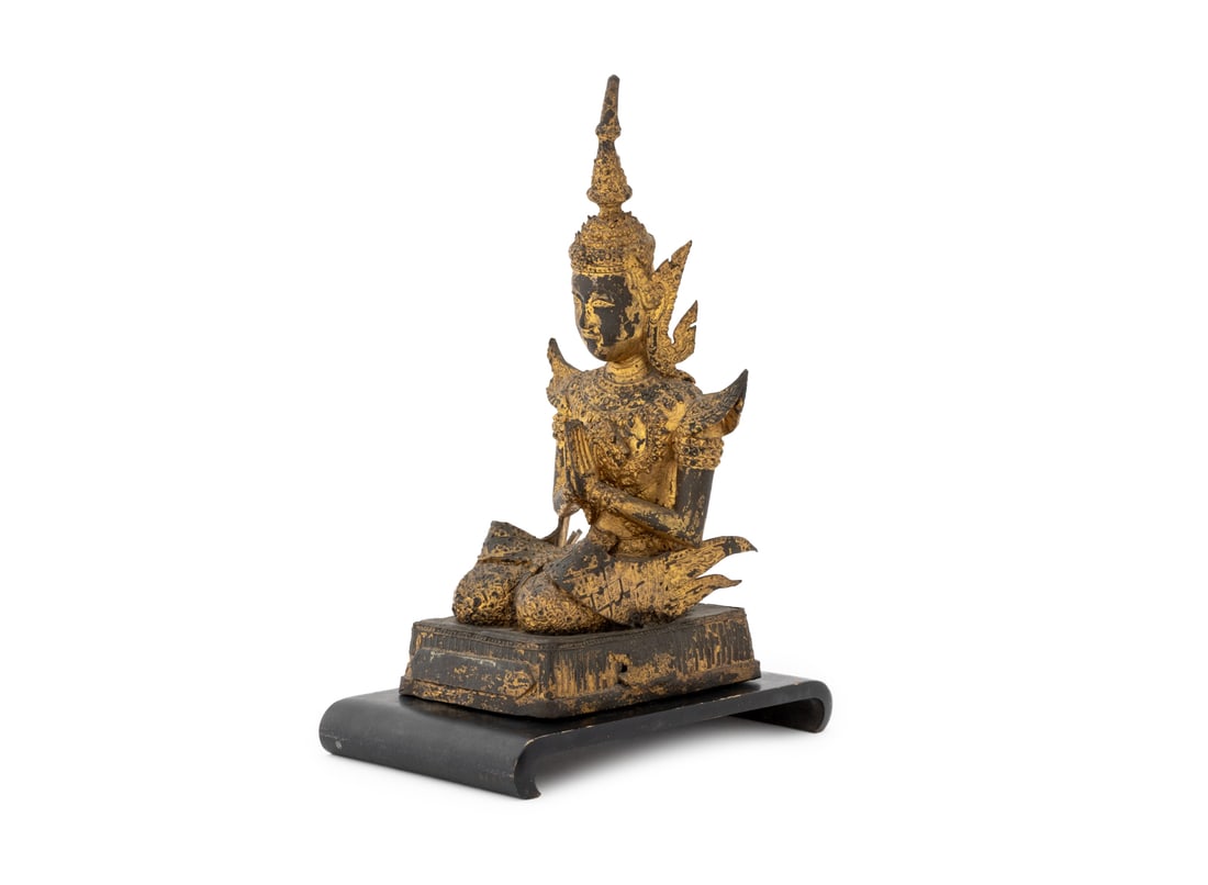 Thai Seated Buddha Gilt Bronze Sculpture: Thai Seated Buddha Gilt Bronze Sculpture, the figure with hands in prayer position and atop a rectangular base, with an ebonized wood stand. Sculpture: 10.25" H x 4.25" W x 5.25" D. Provenance: From