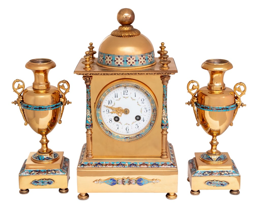French Brass and Champleve Enamel Clock Set, 3: French Polished Brass and Champleve Enamel Three Piece Clock Set, early 20th century, comprising: a clock surmounted by a dome, centered by a painted enamel dial, the movement strike on gong, flanked