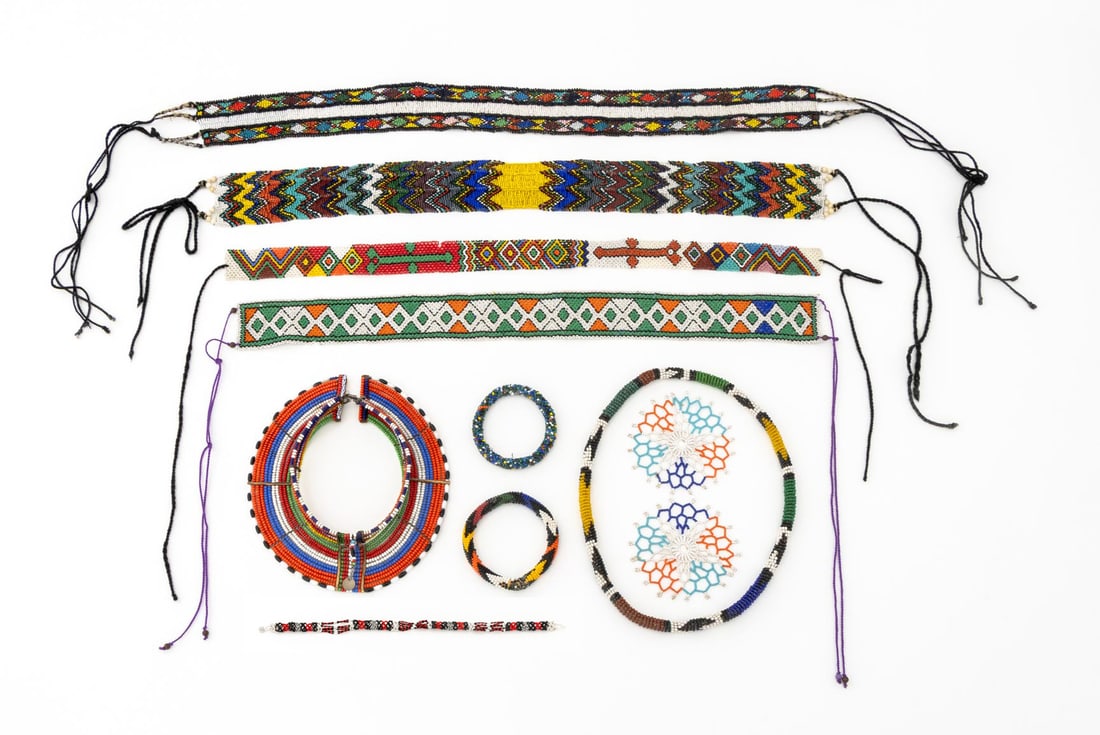 African Polychrome Beaded Jewelry, 11 Pcs.: Group of Eleven African Polychrome Beaded Jewelry Pieces, comprising: two bangles, two blue and orange medallions, and 7 necklaces. Largest: 26" L x 2.5" W. Provenance: From a New York City