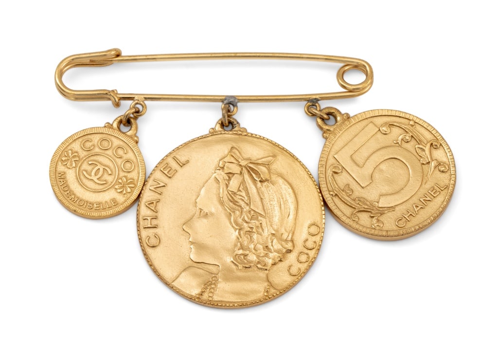 Coco Chanel Gold-Tone Coin Form Brooch: Coco Chanel Gold-Tone Coin Form Brooch, with three separate coins commemorating Coco Chanel with central profile portrait. 2.5" L x 3.5" W. Provenance: From a New York City Collection. Keywords: Jewel