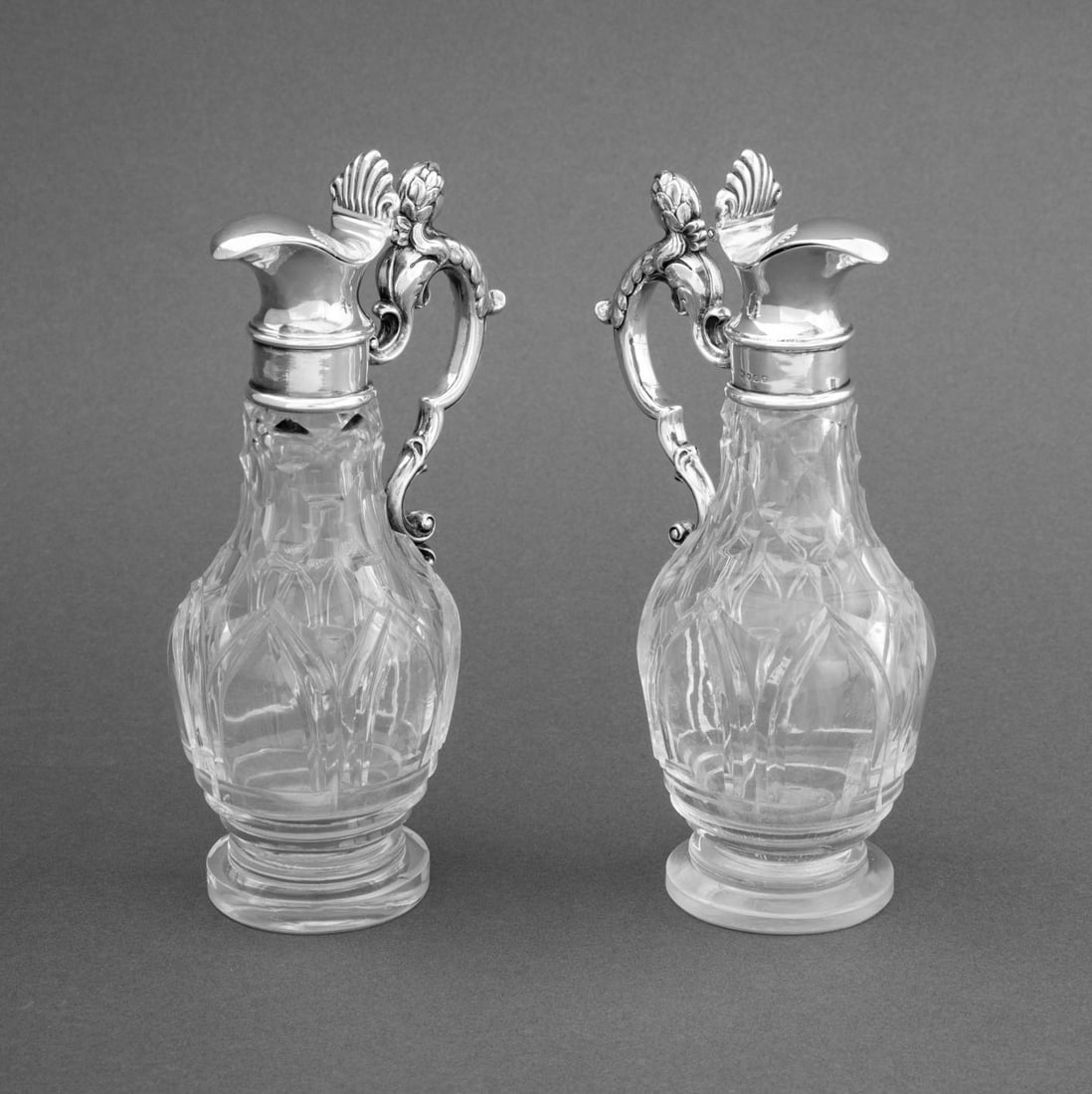 Victorian Sterling and Crystal Claret Jugs, Pair: Pair of Victorian Sterling Silver and Crystal Claret Jugs, struck with marks for Edward and John Barnard, London, 1873, the scroll from handle with Cesar head and shell form spout mounted on cut