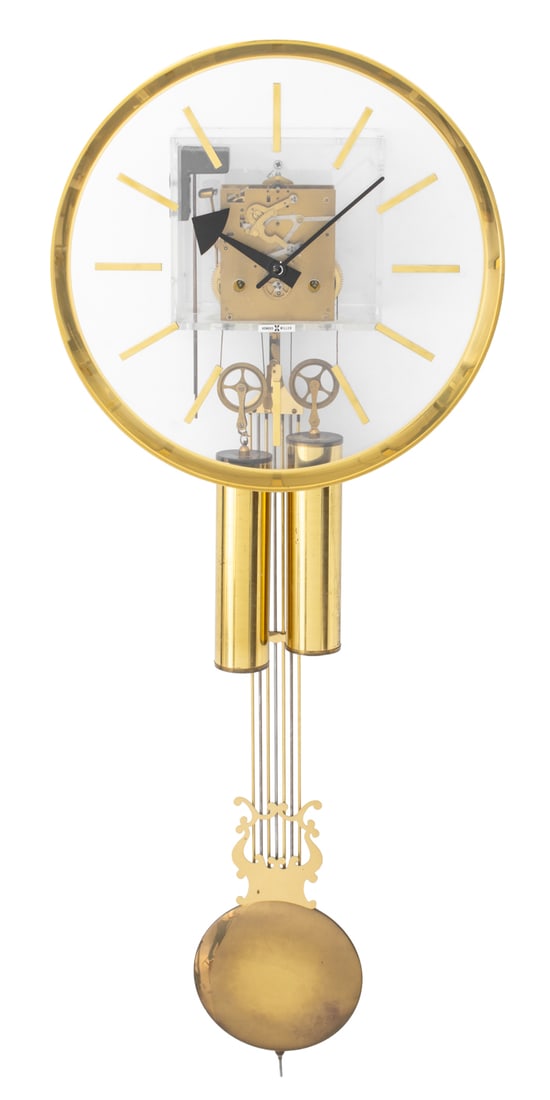 George Nelson for Howard Miller Lucite Wall Clock: George Nelson for Howard Miller Brass and Lucite Wall Clock, hanging pendulum, label to transparent clock face. 40" H x 15" W x 5.5" D. Provenance: From a New York City Collection. Keywords: Timepiece