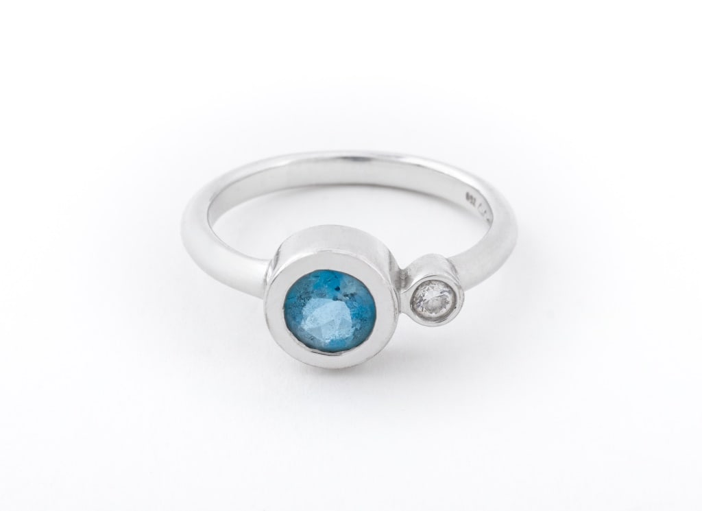 18K White Gold Aquamarine Diamond Ring: 18K White Gold Aquamarine Diamond Ring, featuring one round aquamarine crystal weighing approx. 1.00 carat, adorned with a round diamond weighing approx. 0.10 carat, marked, "750" with maker's marks.