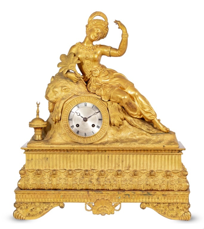 Charles X Gilt Bronze Figural Mantel Clock: Charles X Gilt Bronze Figural Mantel Clock, circa 1830, the circular silvered dial, with strike on bell movement, surmounted by a reclining Turkish woman seated on a tiger skin and brazier beside her,