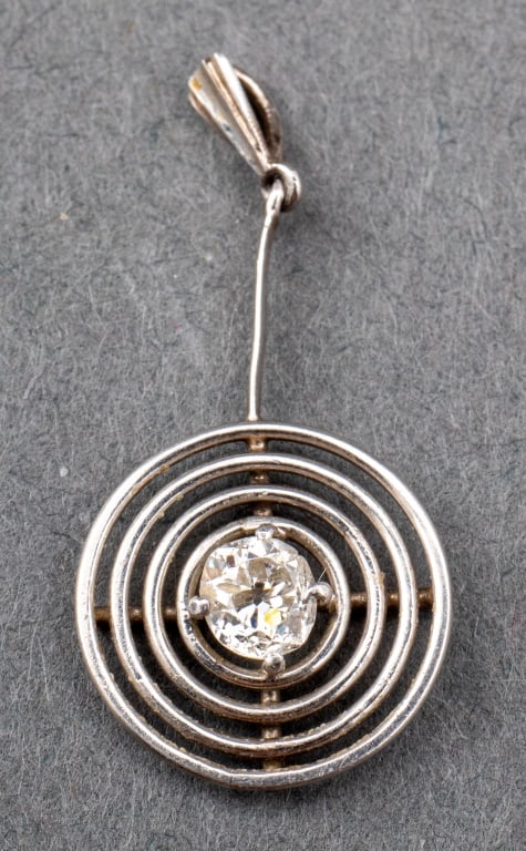 Modernist Platinum & Diamond Circle Drop Pendant: Modernist Platinum and Diamond Concentric Circle Drop Pendant, comprised of one old mine-cut diamond weighing approx. 0.25 carat, color H, clarity I1. 1.06" L x 0.5" W. Platinum tested. Approx: 1.0 dw