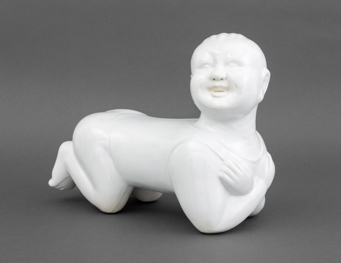 Chinese Blanc de Chine Porcelain Baby Form Pillow: Chinese Blanc de Chine Porcelain Baby Form Pillow. 9.75" H x 12" W x 6" D. Provenance: From a New York City Estate. Keywords: Chinese ceramics, Asian Art, China, Sculpture, Statue, Infant, Figural, Fi