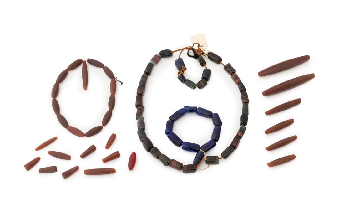 Collection of Carnelian Glass African Trade Beads: Collection of Bohemian and German Carnelian Glass African Trade Beads, together with two strands of mottled agate glass beads. Largest bead: 4.75" L x 0.75" W. Provenance: From the Estate of Jewelry D
