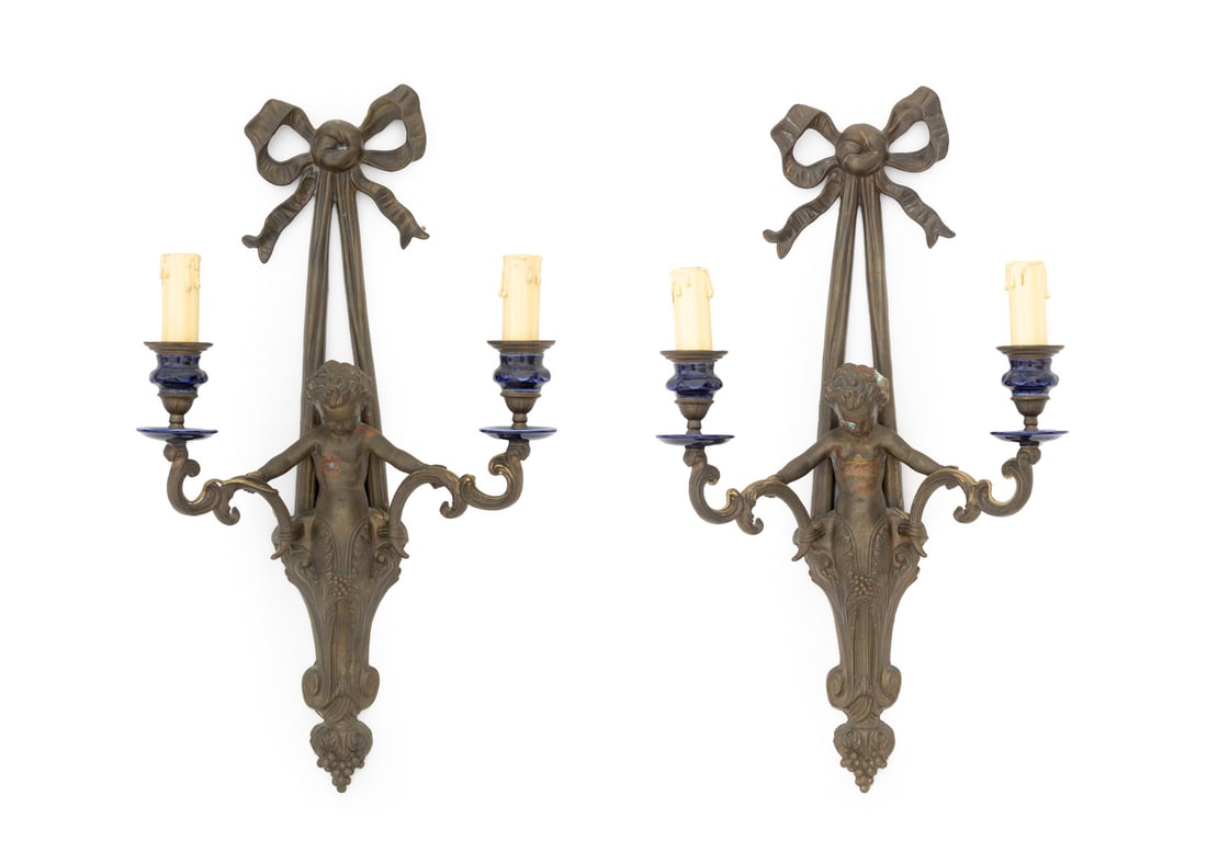 Patinated Brass Cherub Candlestick Sconces, Pair: Pair of Patinated Brass Cherub Candlestick Wall Sconces, two arms with blue ceramic candle base, with ribbon bow top. 22" H x 12" W x 5.25" D. Provenance: From an East 56th Street Collection / Sutton