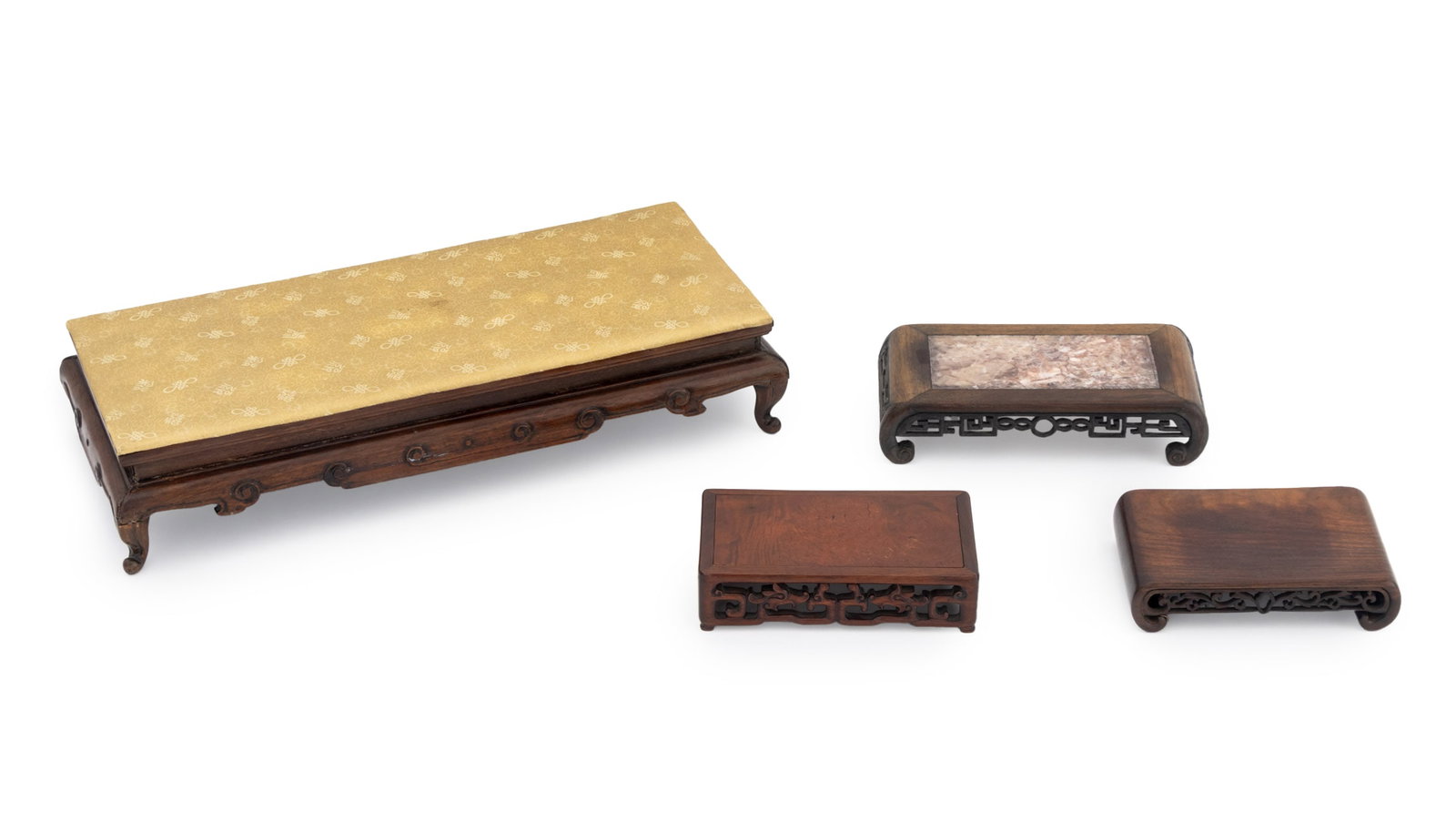 Chinese Carved Wood Display Stands, 4: Collection of Four Chinese Carved Wood Display Stands, with scroll form aprons, one with silk embroidered top, and one with pink marble inset top. Largest: 4.5" H x 22.5" W x 10.5" D. Provenance: From