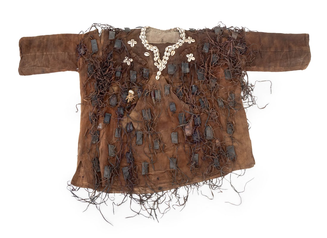 West African Bambara Hunting Tunic: West African Bambara Hunting Tunic, probably Ivory Coast, fabric mounted with cowrie shells and amulets including chicken feet, animal hide, and horn. 31.25" H x 55.5" W. Provenance: From a Manhattan