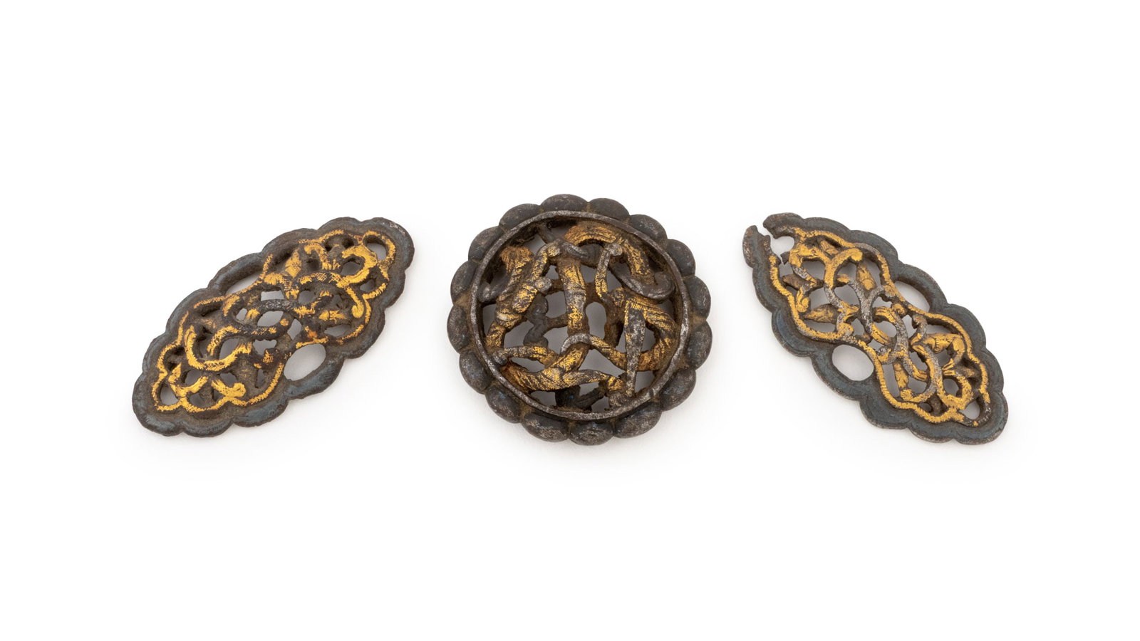 Chinese Tibetan Gilt Iron Saddle Mounts, 3: Collection of Three Chinese Tibetan Gilt Iron Horse Saddle Mounts, 19th century or earlier, each with reticulated scrolling design and one circular with dragon motif. Oblong medallion: 2" L x 1" W x 0