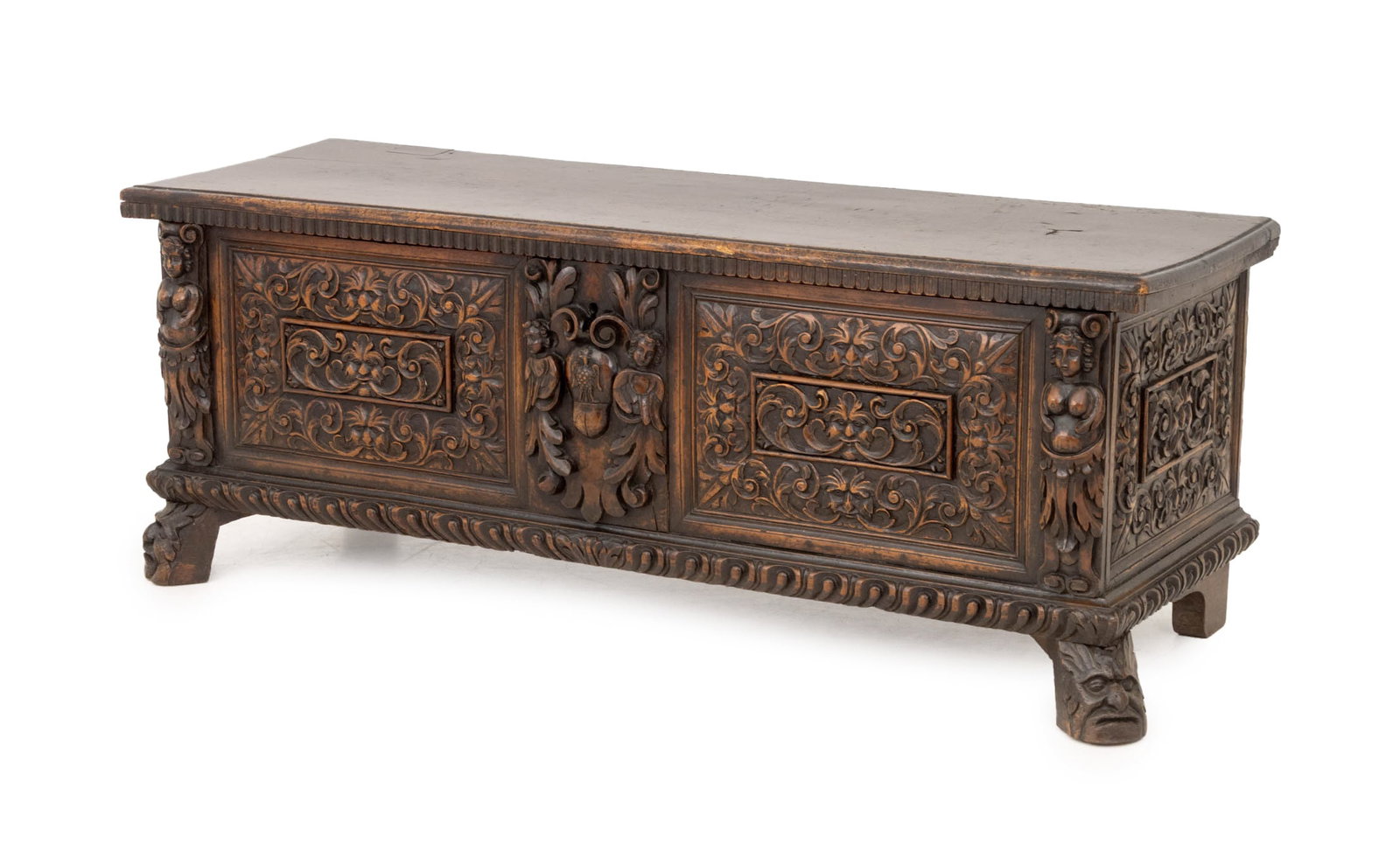 Italian Baroque Carved Walnut Blanket Chest: Italian Baroque Figural Carved Walnut Wood Cassone, the front face with Green Man masques and scrolling foliate motifs, label to reverse. 24" H x 62.5" W x 21" D. Provenance: The Estate of Gilbert C.