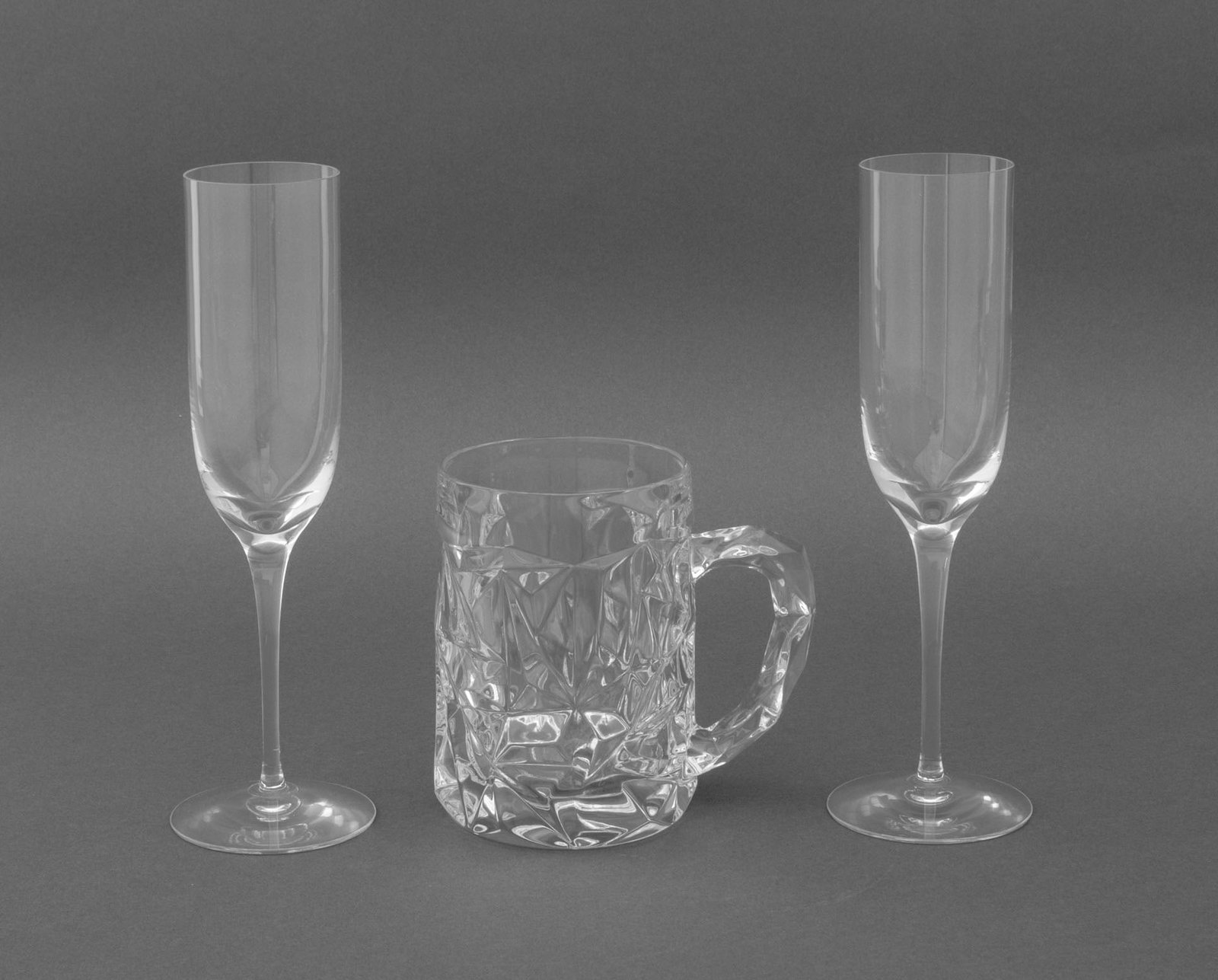 Tiffany & Co. Glassware, 3 Pcs.: Group of Three Tiffany and Company Glassware Pieces, all marked and "Tiffany & Co." and comprising: a pair of champagne flutes and a "Rock Cut" crystal beer mug. Flute: 9" H x 2.75" Diameter; mug: 5"