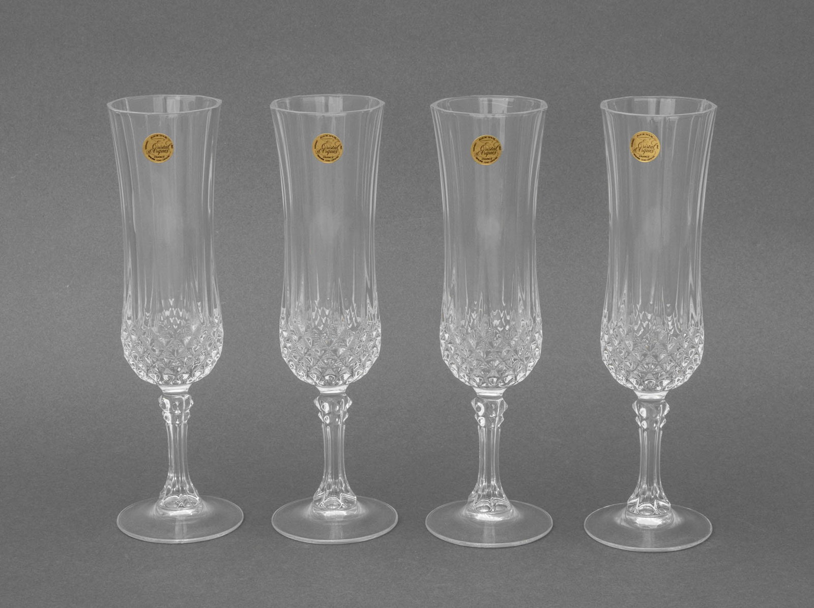 Longchamp Crystal Champagne Flutes, 4: Set of Four Longchamp Crystal Champagne Flutes, diamond-cut glass with label "Cristal d'Arques / France / Garanti / Genuine Lead Crystal", with original box. 8" H x 2.5" Diameter; box: 8.75" L x 10.75