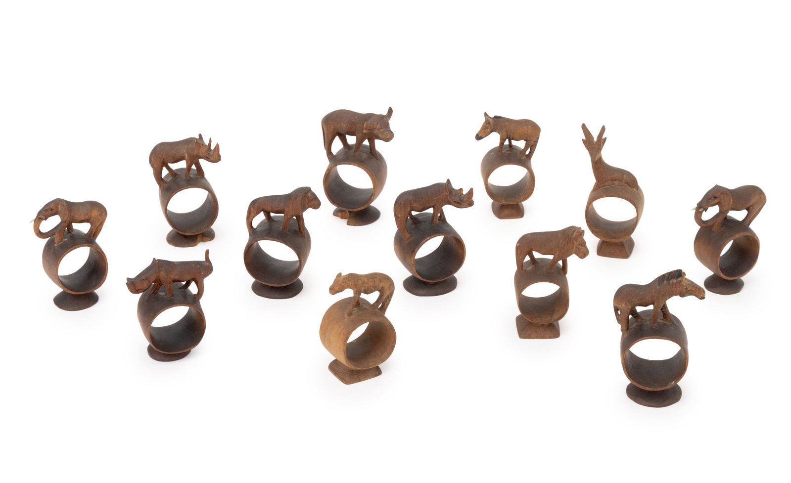 Folk Art Carved Wood Animalier Napkin Rings, 12: Set of Twelve Folk Art Carved Wood Animalier Napkin Rings, comprising: pair of elephants, pair of rhinoceroses, pair of lions, pair of zebras, a gazelle, a water buffalo, a warthog, and a lioness. 4.2