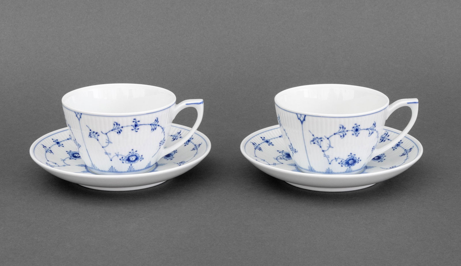 Royal Copenhagen "Blue Fluted Plain" Teacups, 2: Set of Two Royal Copenhagen "Blue Fluted Plain" Porcelain Teacups and Saucers, each marked "Royal Copenhagan / Handpainted / Since 1775 / 087" underside, with original box. Overall: 3" H x 6.5" Diamet