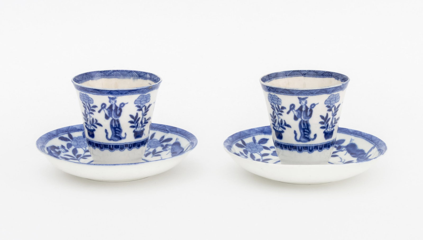 Dutch Chinoiserie Style Teacups and Saucers, Pair: Pair of Dutch Chinoiserie Style Blue and White Porcelain Tea Cups and Saucers, with figural decoration. Cup: 3" H x 3" Diameter; saucer: 5.25" Diameter x 1" H. Provenance: The Estate of Alton G. Marsh