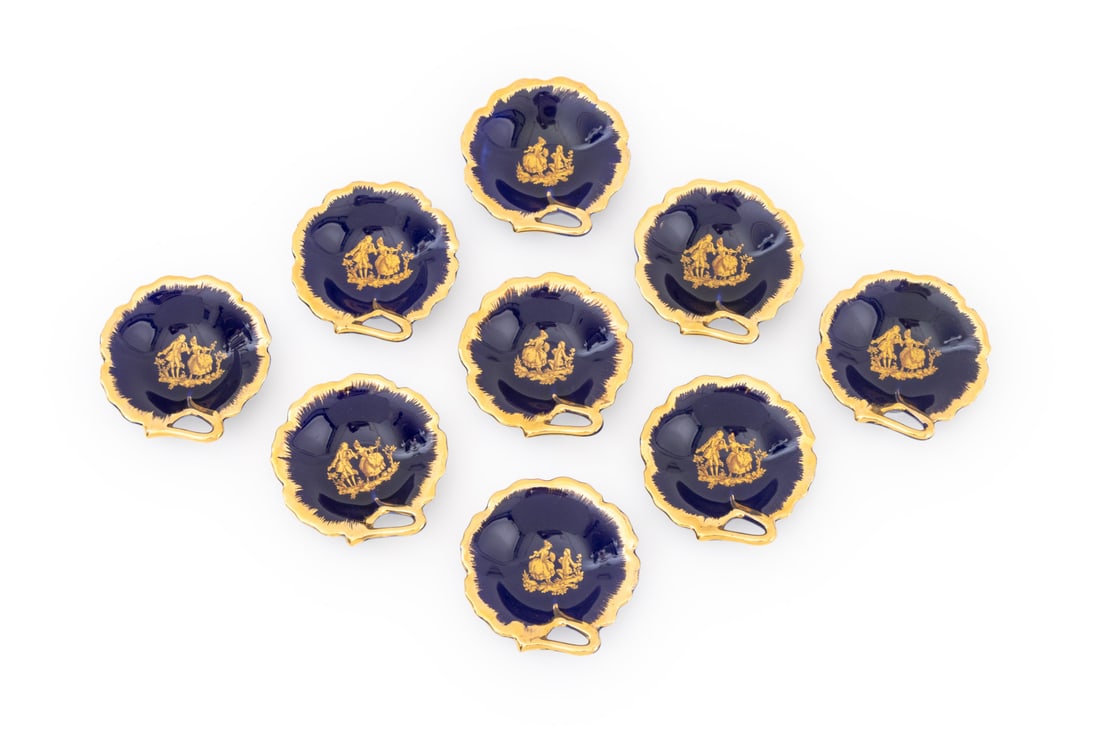 Limoges Gilt Cobalt Blue Porcelain Leaf Dishes, 9: Set of Nine Limoges Gilt and Cobalt Blue Glazed Leaf Form Trinket Dishes, each with couple courting scene to bowl and marked "Limoges / made in France". Veritable Porcelaine d'Art" to underside. 3.25"