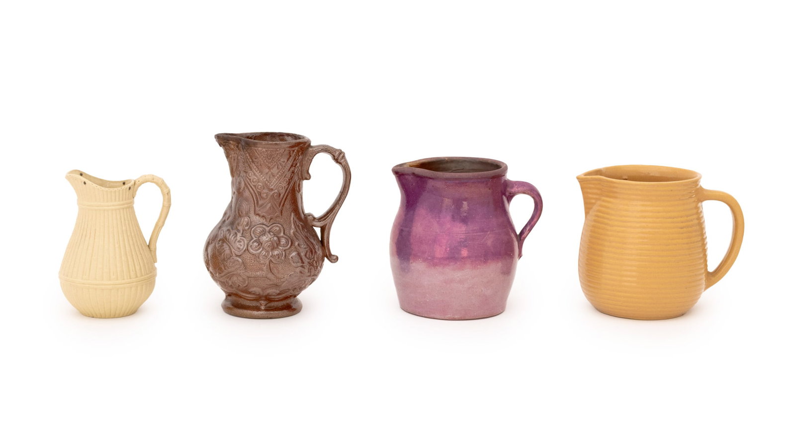 Collection of American Pottery Jugs, 4: Collection of Four American Pottery Jugs, comprising: a Monmouth pottery beehive pitcher glazed mustard yellow and with maple leaf mark to underside, a Victorian salt-glazed stoneware jug, a purple