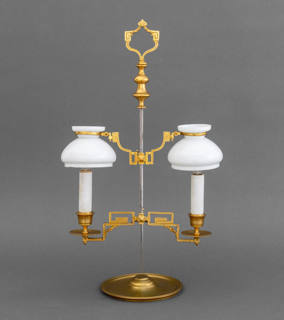 American Brass Double Students Lamp: American Brass Double Students Lamp, with Greek key motif and milk glass shades. 19.75" H x 11.5" W x 6" D. Provenance: From a 21 East 87th Street Estate. Keywords: Keywords: Lighting, Table lamp, Mod