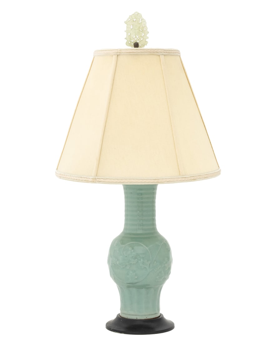 Chinese Celadon Glazed Vase Mounted as a Lamp: Chinese Celadon Glazed Ceramic Vase Mounted as a Table Lamp, the vessel of Phoenix Tail vase form with molded scrolling foliate motif, and mounted atop an ebonized circular base, with beige shade and 