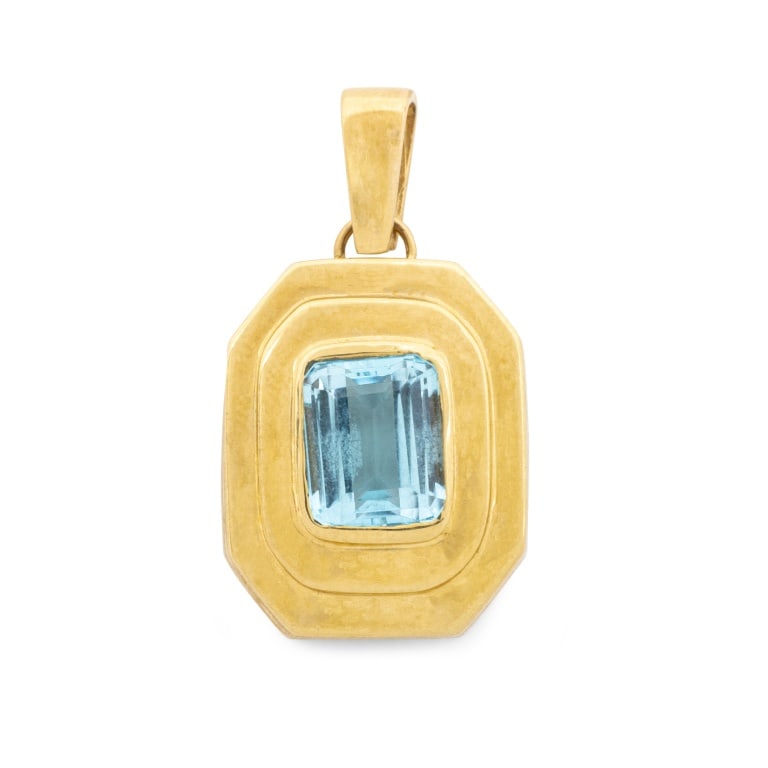Octagonal Yellow Gold Blue Topaz Pendant: Octagonal 14K Yellow Gold Blue Topaz Pendant, featuring one centered bezel set emerald cut blue topaz weighing approx. 7.00 carats. Gold tested. Measuring approx. 1 1/2" x 3/4", 6.0 dwt. Provenance: F