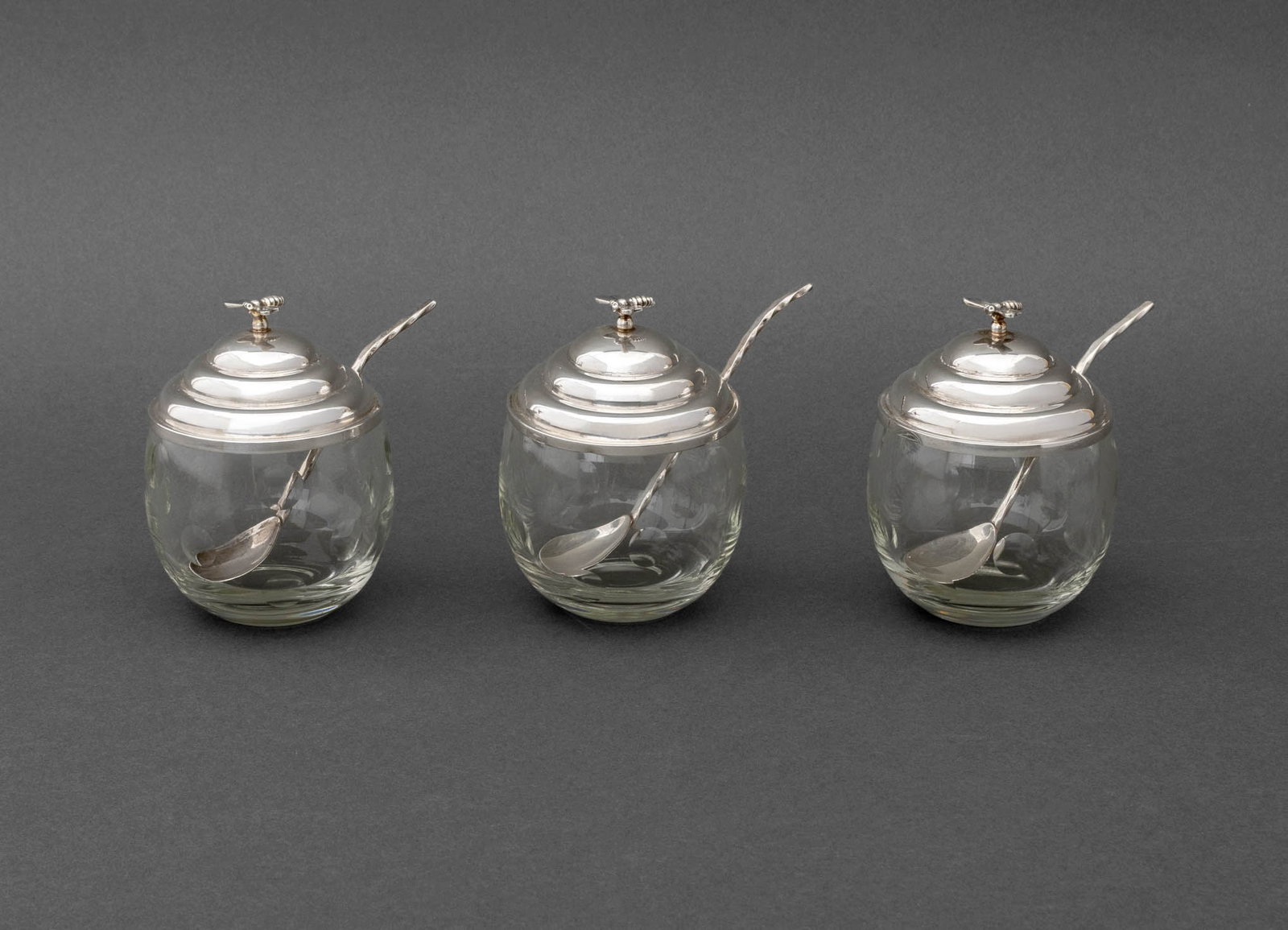 Cartier Sterling Silver and Glass Honey Pots, 3: Set of Three Cartier Sterling Silver and Glass Honey Pots, with bee form knops and matching spoons, marked "Cartier / Sterling". Silver weight only: 4.40 ozt.; overall: 4.25" H x 4.25" W x 3.25" D.