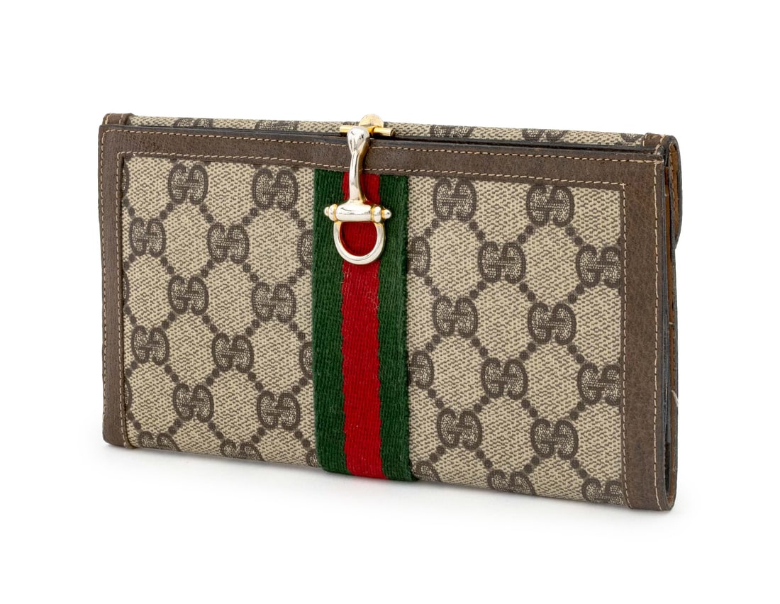 Gucci Monogram Supreme Leather Wallet: Gucci GG Monogram Supreme Leather Wallet, with red and green cotton stripe, gold-tone metal clasp opening to divided interior and single outer pocket, marked "Gucci / Made in Italy". 7.25" H x 4" W x 