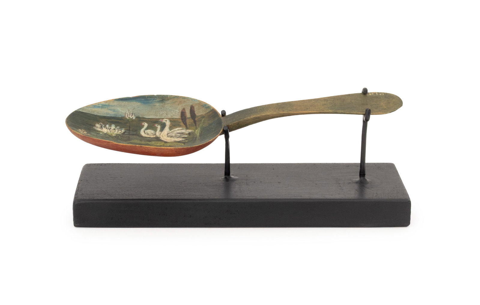 American Folk Art Painted Carved Wood Spoon: American Folk Art Polychrome Painted and Carved Wood Spoon, with swan landscape scene to the bowl, together with ebonized wood stand. Overall: 3" H x 8.25" W x 2.5" D. Provenance: From a 21 East 87th 