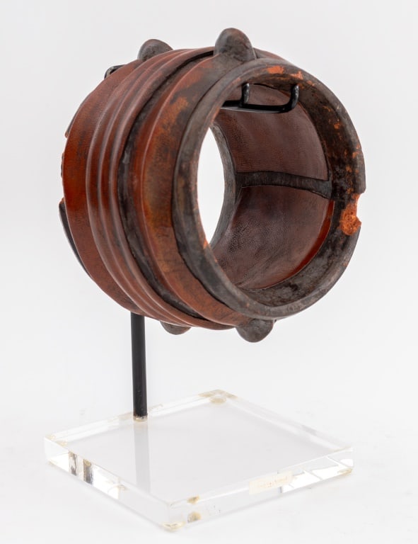 Leather and Terracotta Bangle: Leather and Terracotta Bangle, possibly African, on a fitted Lucite stand. Bangle: 3.5" H x 4.5" Diameter. Provenance: From a Sutton Place Estate. Keywords: Jewelry, Bracelet, Cuff, Handmade,