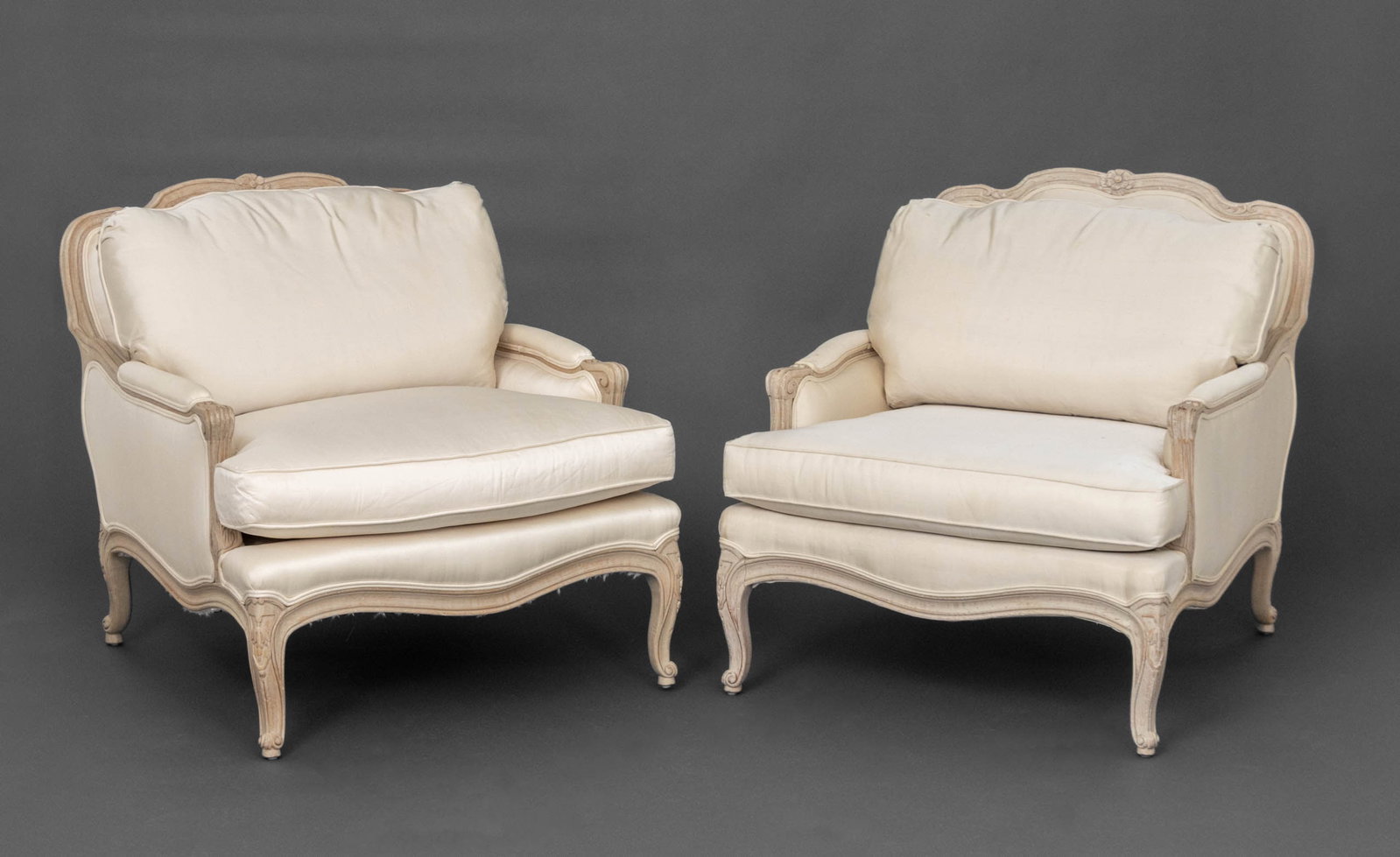 Louis XV Style White Upholstered Bergeres, Pair: Pair of Louis XV Style White Fabric Upholstered Cerused Wood Bergeres, with Interior Crafts labels beneath cushions. 32.75" H x 31" W x 36" D; seat: 18" H. Provenance: From a 500 Park Avenue Estate. K
