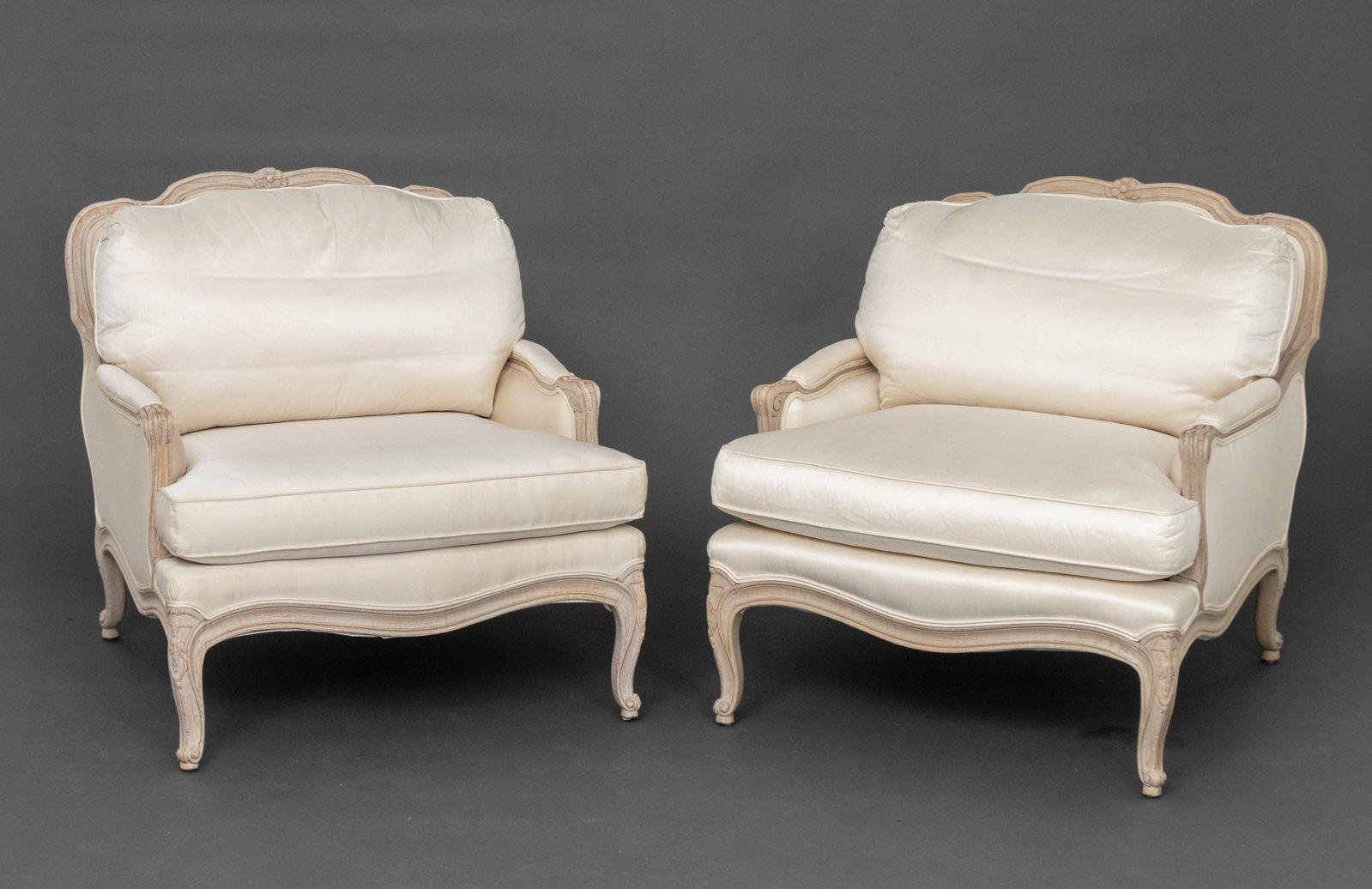 Louis XV Style White Upholstered Bergeres, Pair: Pair of Louis XV Style White Fabric Upholstered Cerused Wood Bergeres, with Interior Crafts labels beneath cushions. 32.75" H x 31" W x 36" D; seat: 18" H. Provenance: From a 500 Park Avenue Estate. K