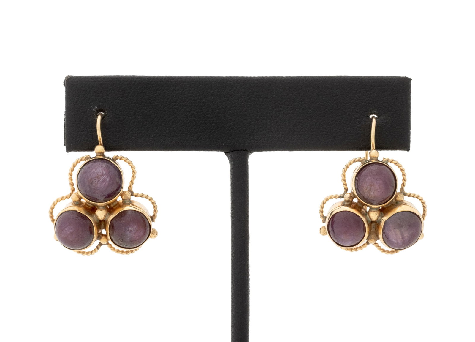 Star Ruby and Yellow Gold Earrings: Pair of 14K Yellow Gold and Star Ruby Earrings, featuring six bezel set round cabochon star rubies weighing a total of approx. 24.00 carats, worn through pierced earlobes with shepherd's hook