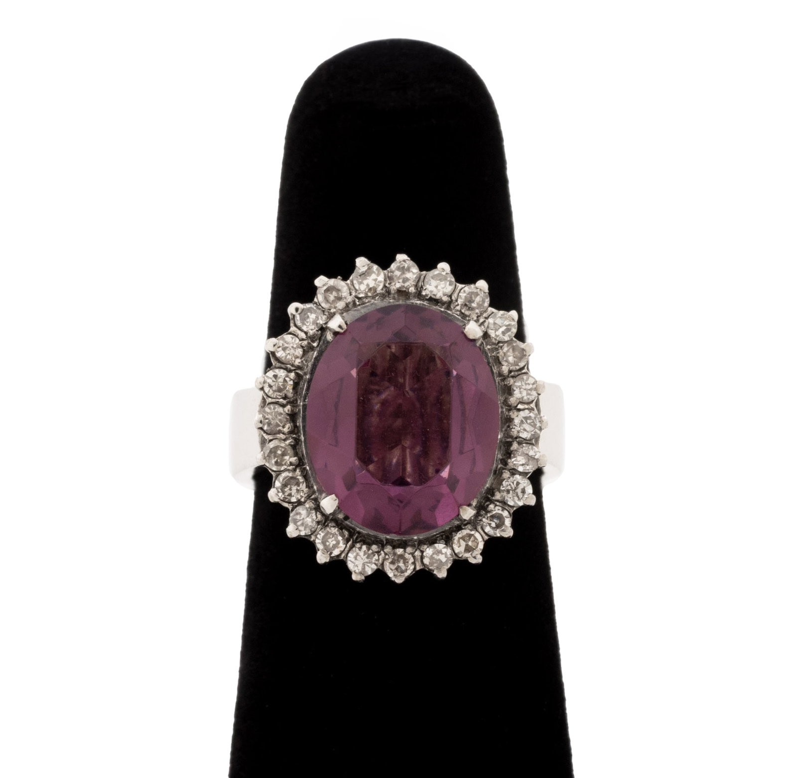 Purple Gemstone, Diamond, and White Gold Ring: Purple Gemstone, Diamond, and 10K White Gold Ring, featuring one prong set oval purple faceted gemstone approx. 12 x 10 mm., further adorned with twenty four prong set single cut diamonds weighing a t