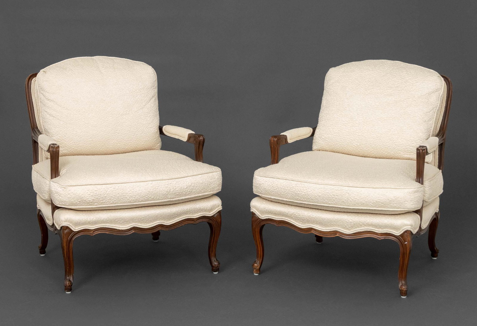 Louis XV Style Upholstered Walnut Bergeres, Pair: Pair of Louis XV Style Cream Fabric Upholstered Walnut Bergeres. 34.5" H x 30" W x 30" D; seat: 19" H. Provenance: From a 500 Park Avenue Estate. Keywords: Vintage Furniture, Seating, Armchairs,