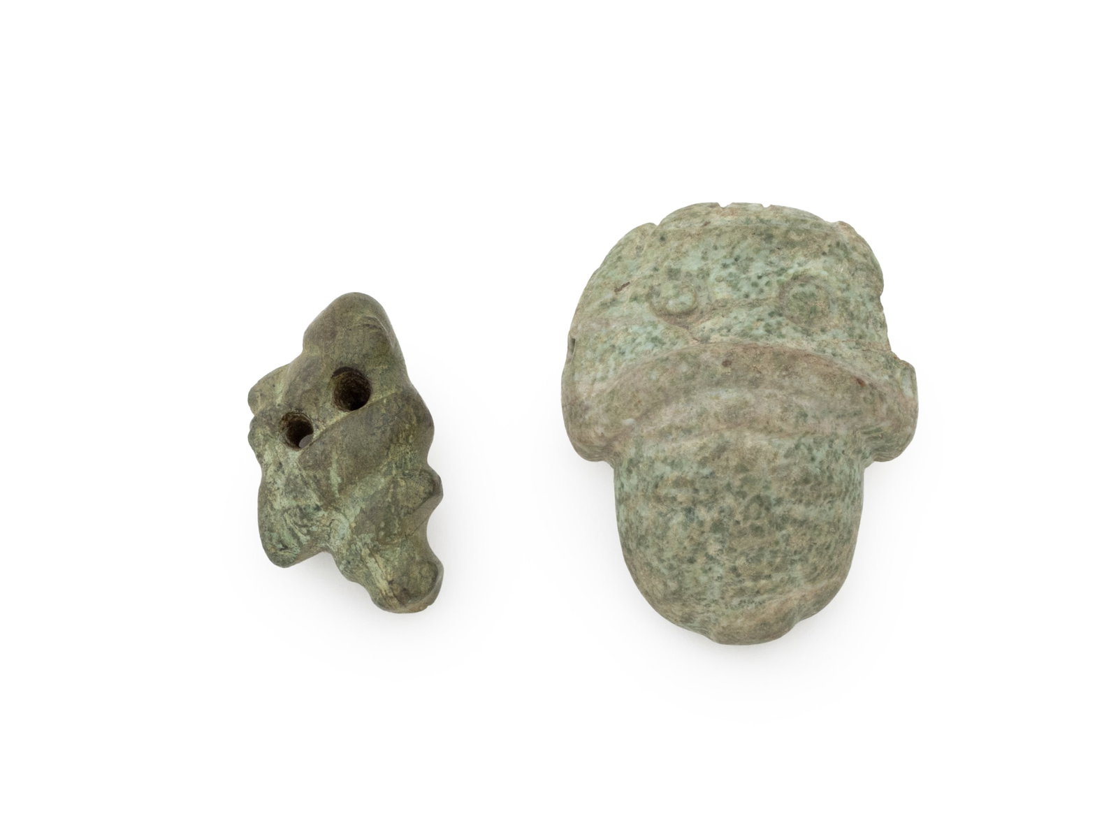 Mesoamerican Pre-Columbian Jade Carvings, 2: Two Mesoamerican Pre-Columbian Jade Carvings, one pendant in the form of a mask adorned in a headdress, and one in the form of a frog. Larger: 2" H x 1.5" W x 0.5" D. Provenance: From an Upper West Si
