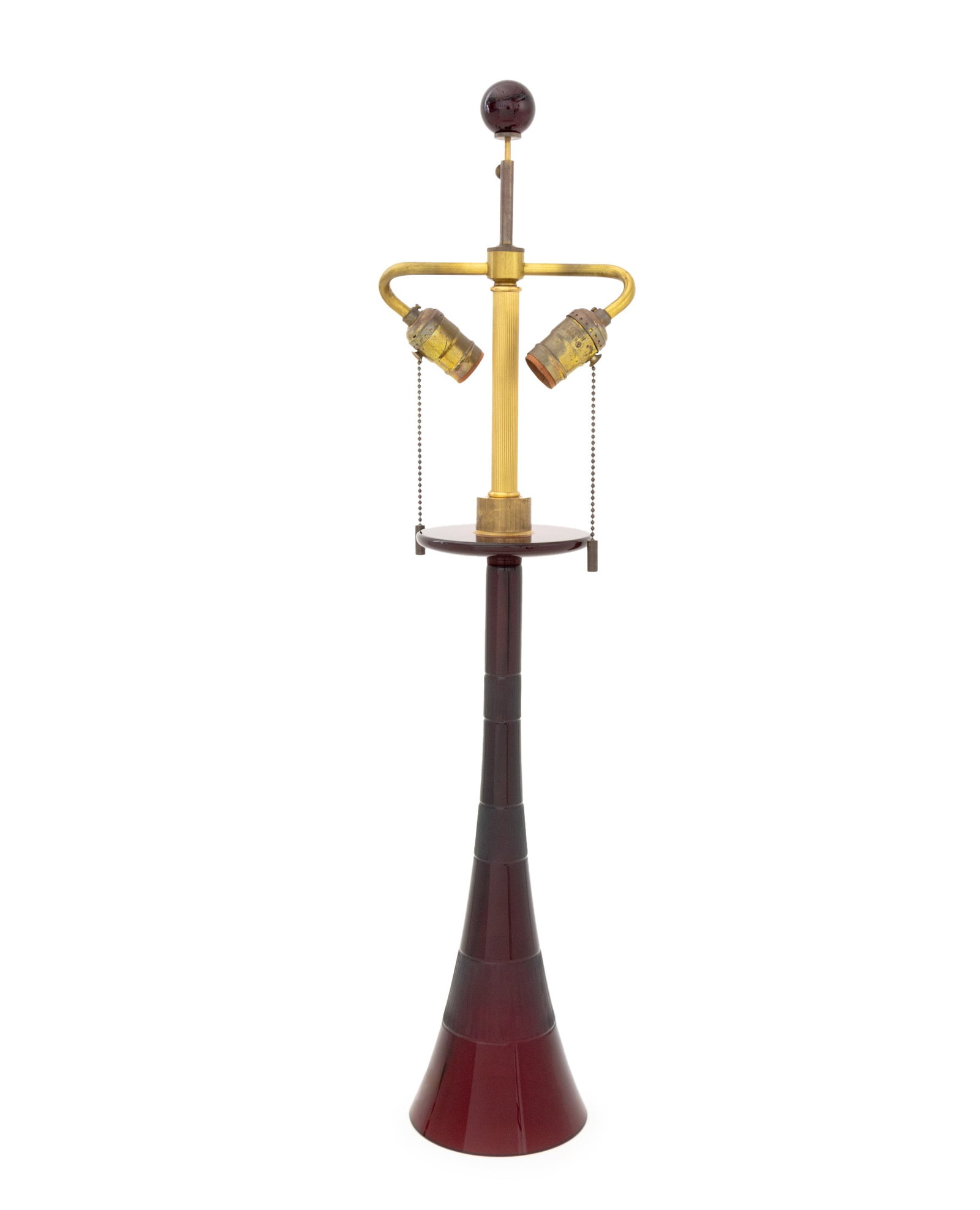 John Hutton x Donghia Ruby Murano Glass Lamp: John Hutton for Donghia Ruby Red Murano Glass Lamp, conical glass base with striped pattern, signed "John Hutton", with two sockets and ruby glass finial. 31" H x 5.75" Diameter. Provenance: From a