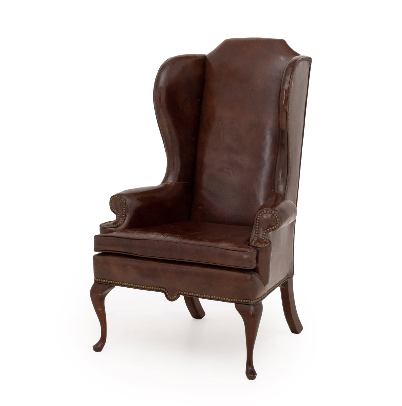 American Studded Upholstered Wingback Armchair: American Queen Anne Style Brass Nailhead Studded Brown Vinyl Upholstered Wingback Arm Chair, atop walnut cabriole legs, Bloomingdale Brothers label beneath seat. 50.5" H x 31" W x 24" D; seat: 21" H.