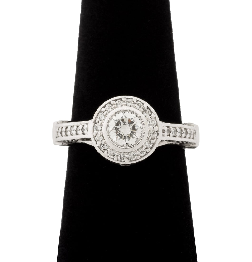 White Gold and Diamond Halo Engagement Ring: 14K White Gold and Diamond Halo Engagement Ring, featuring one centered bezel set round brilliant cut diamond, weighing approx. 0.60 carat, J-K color / SI1 clarity, further adorned with 98 round brill