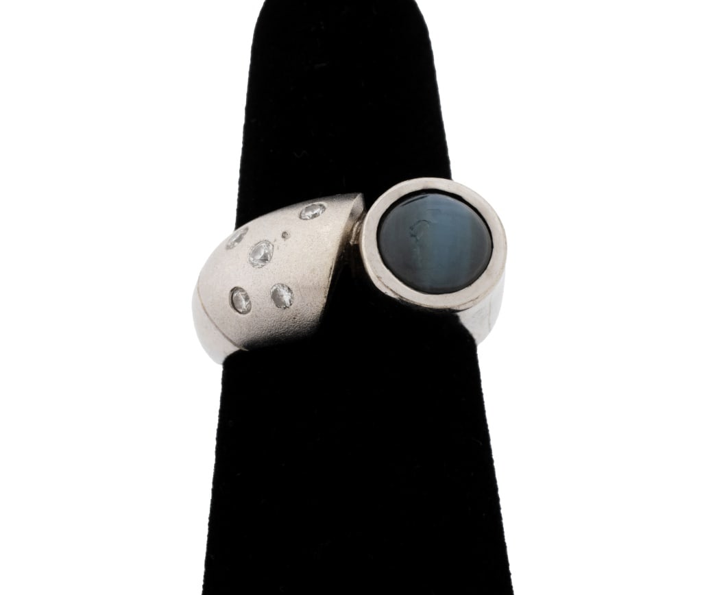 White Gold, Hawk's Eye Chrysoberyl, & Diamond Ring: Modern 18K White Gold, Hawk's Eye Chrysoberyl, and Diamond Ring, brightly polished and sand blast finished, featuring one bezel set round cabochon cat's eye chrysoberyl weighing approx. 2.50 carats,
