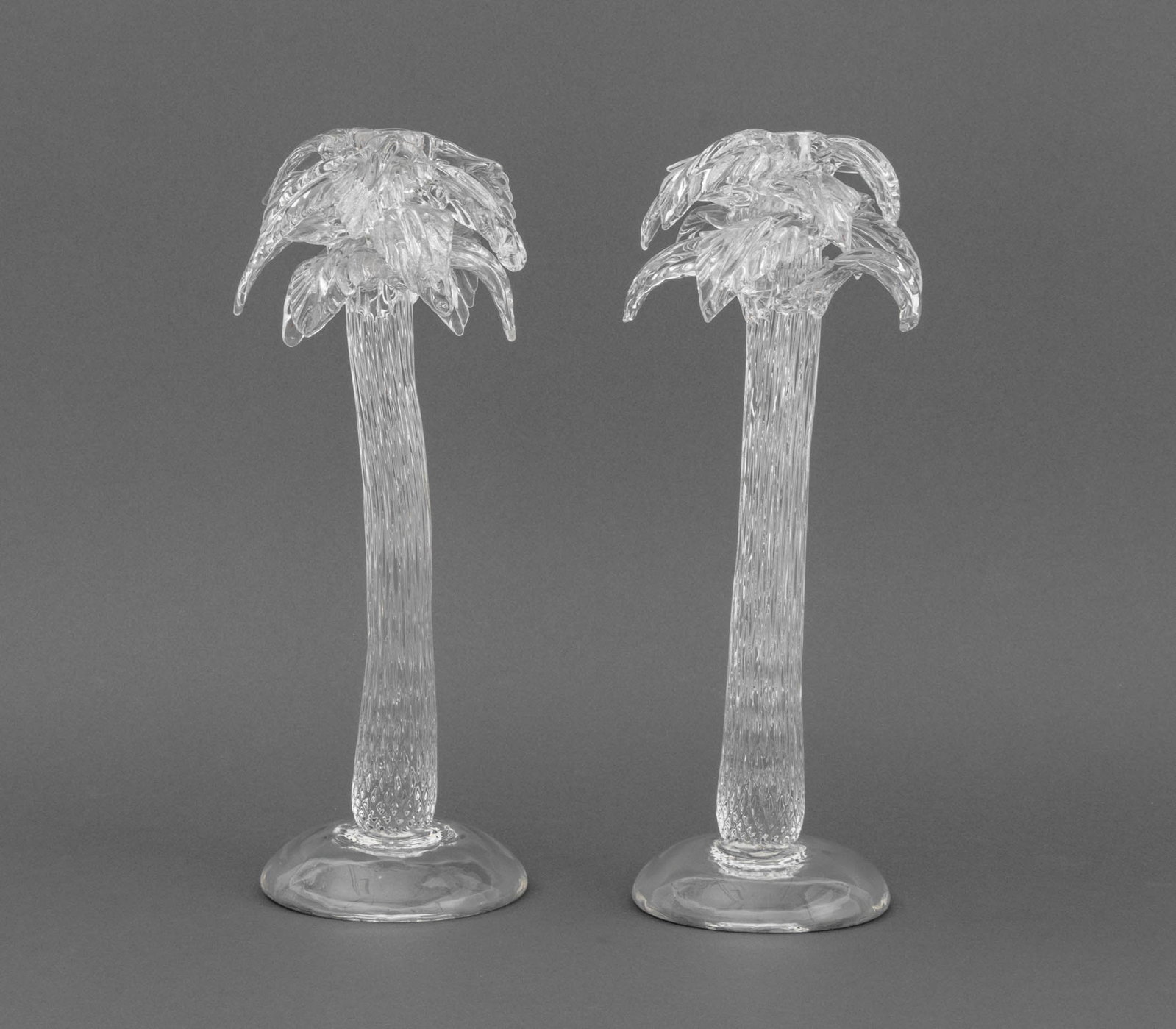 Murano Glass Palm Tree Form Candlesticks, 2: Pair of Murano Clear Art Glass Palm Tree Form Candlesticks. 15.25" H x 6.25" Diameter. Provenance: From a Fort Lauderdale, Florida Estate. Keywords: Studio Glass, Glassware, Lighting, Candle holder, I