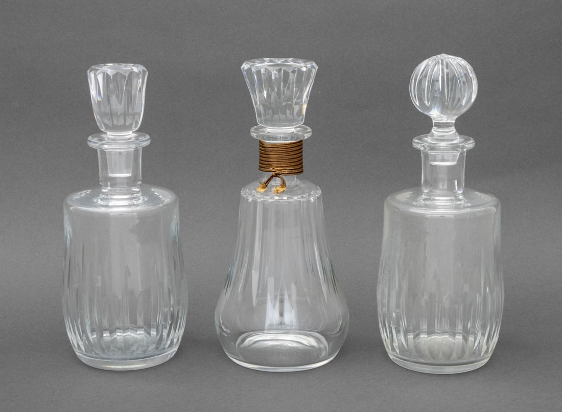 Baccarat Cut Crystal Decanters, 3: Group of Three Baccarat Cut Crystal Decanters, one with gold-tone cord wrapped around neck, each marked to underside. Tallest: 10" H x 4.5" Diameter. Provenance: From an East 86th Street Estate. Keywo