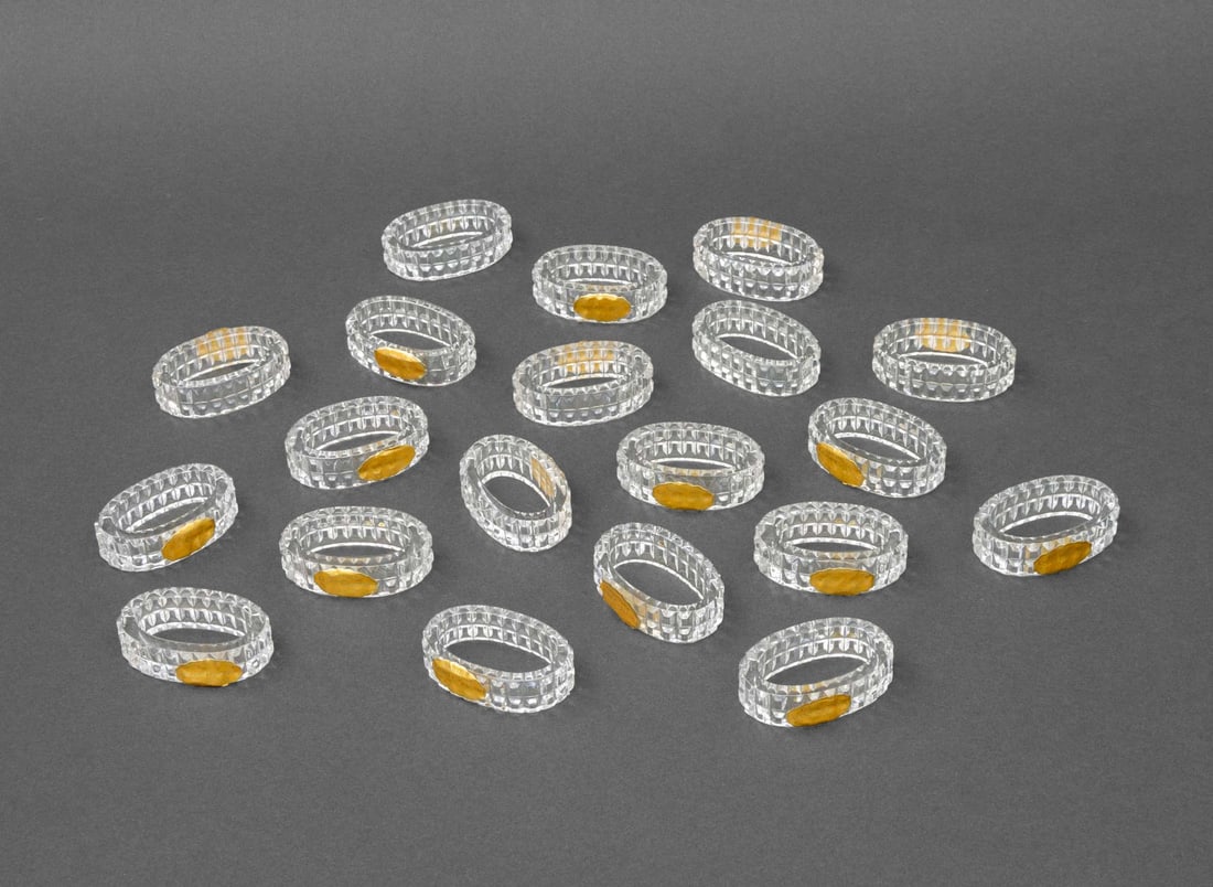 German Faceted Crystal Napkin Rings, 20: Set of Twenty German Faceted Crystal Napkin Rings, some with "Genuine Lead Crystall / 24% PbO / Made in Western Germany" labels. 2.25" L x 1.5" W x 0.75" D. Provenance: From a New York City Collection